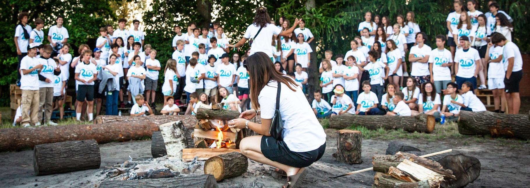 Campers and counselors gathered around an outdoor campfire