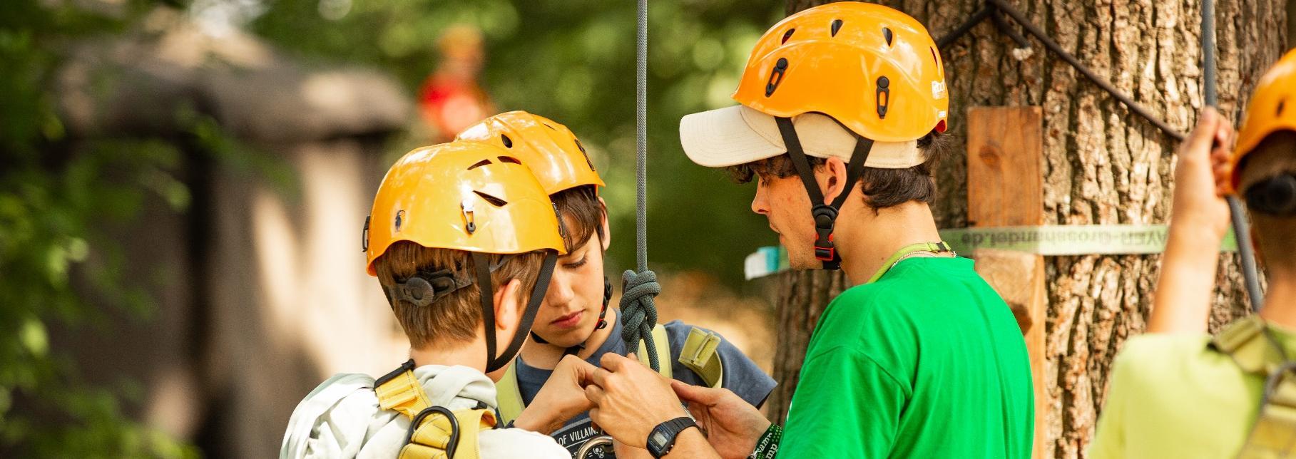 An instructor helping participants prepare for a ropes activity