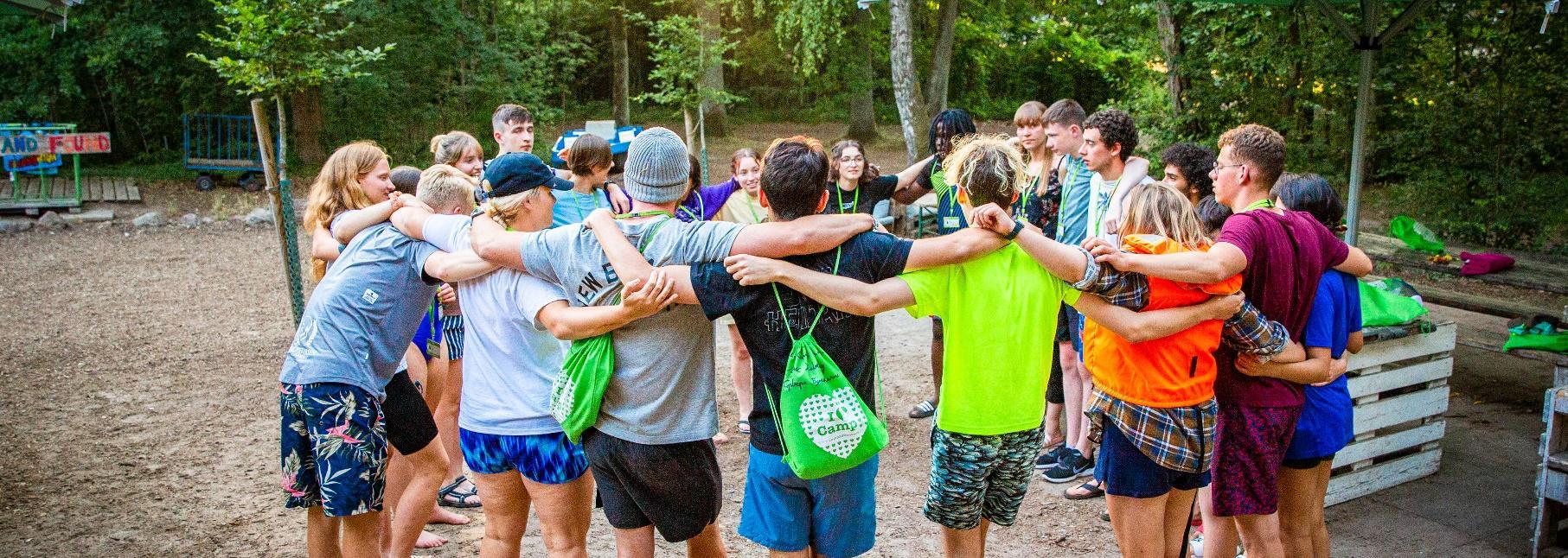 Counselors making a circle together in the forest